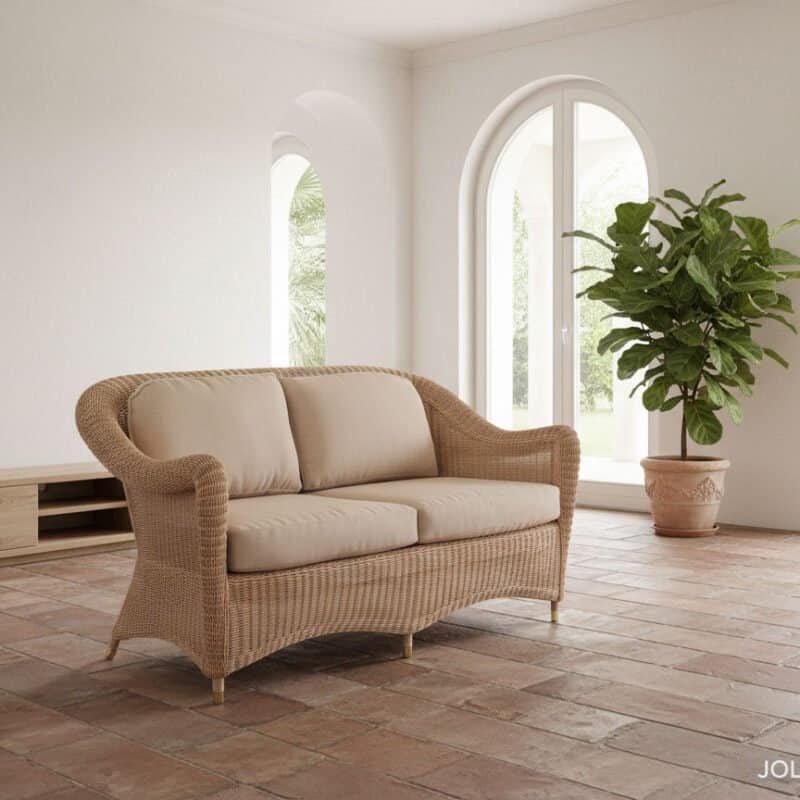 Divano in vimini beige in soggiorno luminoso con grandi finestre.