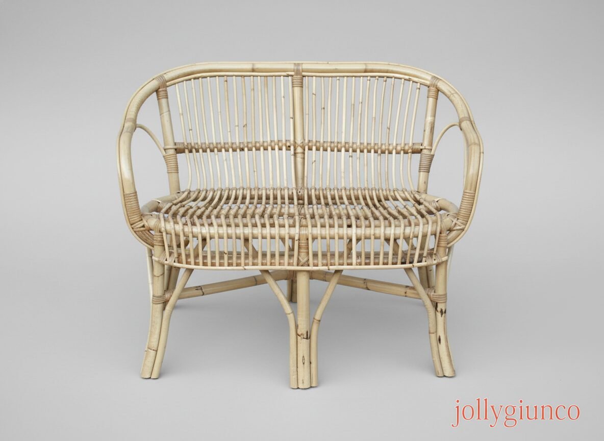 Divano Barina in giunco 2 jollygiuncoeu beige wicker chair with curved arms and a woven seat in a neutral studio setting on a gray background
