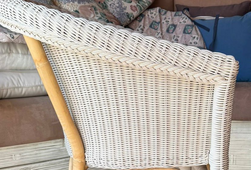 PoltroncinaMaltaPozzettopolyrattan jollygiuncoeu wicker chair with a curved braided top edge and a wooden armleg shown from the side indoors