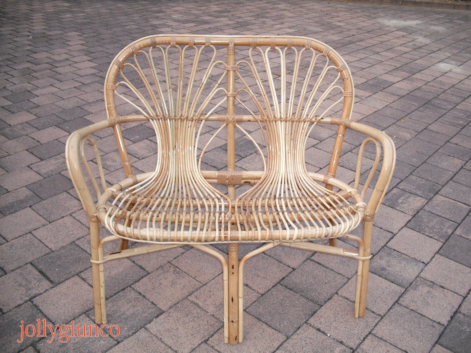 poltronasole1g jollygiuncoeu wicker rattan chair with curved arms on a brick paved surface showcasing woven back and seat patterns