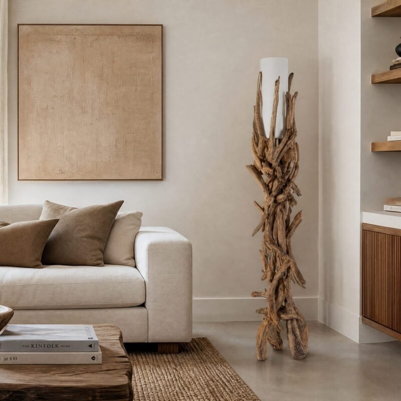Cozy beige living room with a plush sofa, brown cushions, a large beige-framed artwork, and driftwood sculpture beside a white lamp.