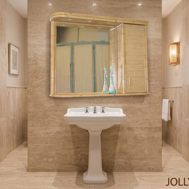 Beige marble bathroom with a white pedestal sink and a bamboo-framed mirror cabinet; two turquoise vases on the sink.