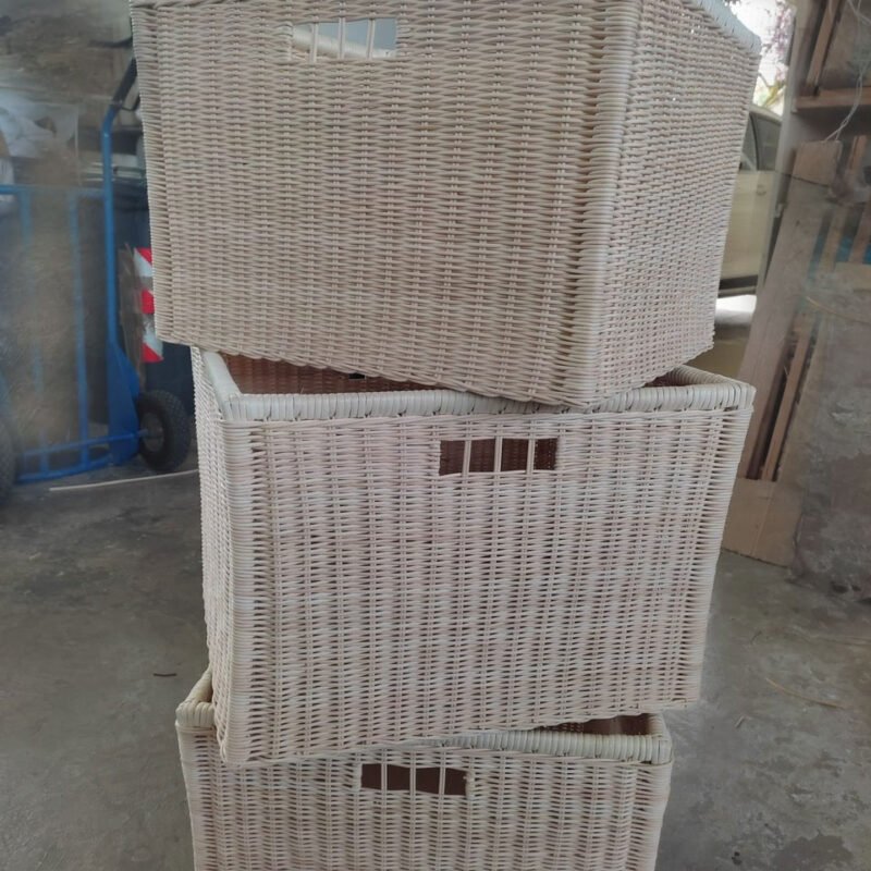 Stack of three light beige woven wicker storage baskets stacked in a workshop setting