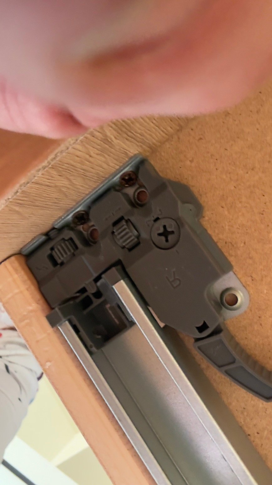 IMG2788 jollygiuncoeu close up of a gray sliding door mechanism mounted to a wood surface with a finger visible in the upper left corner