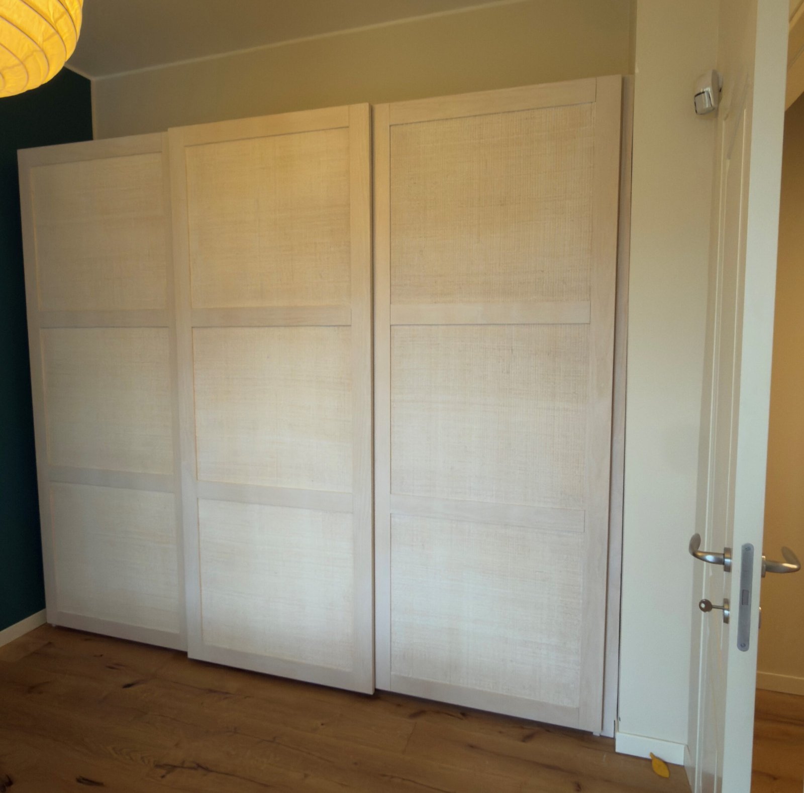 Armadio Erice a 3 Ante Scorrevoli con cassettiera1 2 jollygiuncoeu white paneled wardrobe doors in a living space with a wooden floor and a yellow leaf near the baseboard the room has a dark wall on the left and a door handle visible on the right