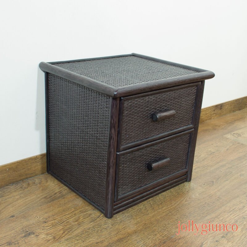 Dark brown wicker bedside cabinet with two drawers, set against a white wall on a wooden floor.